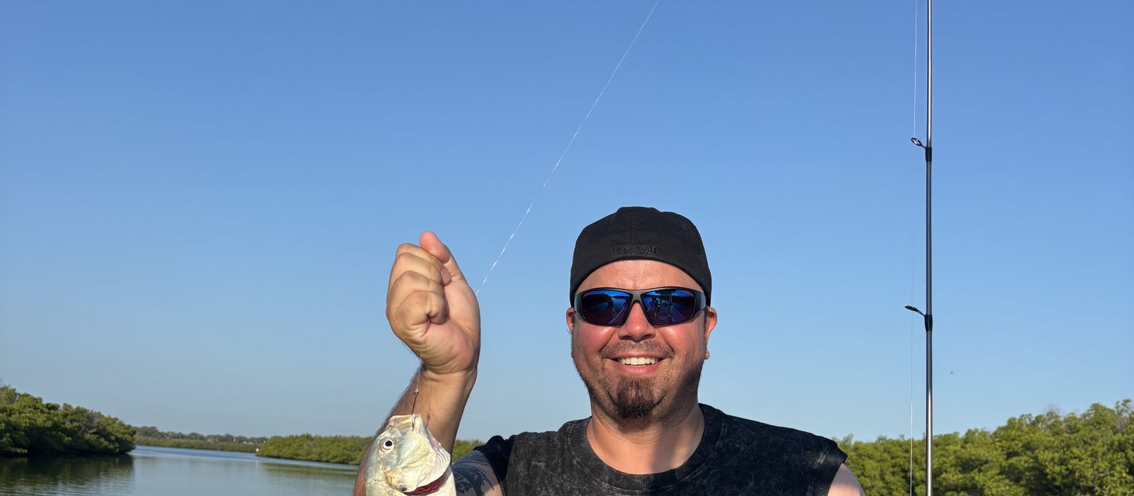 Angler fighting a hooked redfish on a New Smyrna Beach inshore fishing charter, Mosquito Lagoon flats in the background
